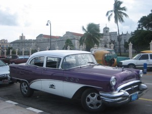 A classic American car from the fifties next to a remaining segment of the old city walls in Havana